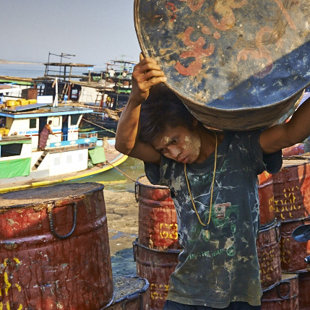 Empty cane barrels is being loaded by child labor, Irrawaddy River, Mandalay